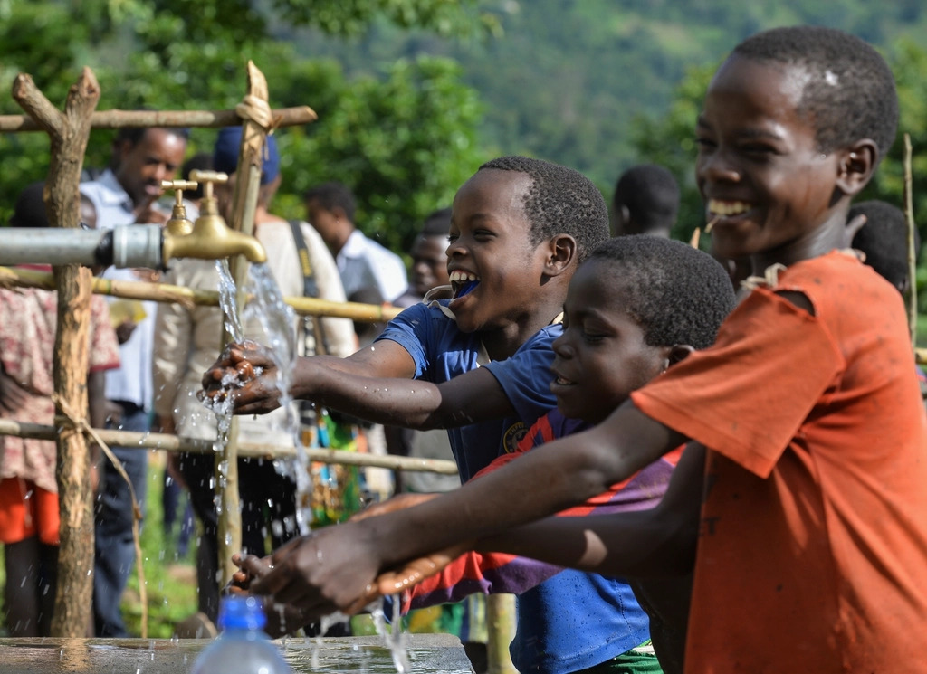 Children washing hands and drinking at an outdoor water-point