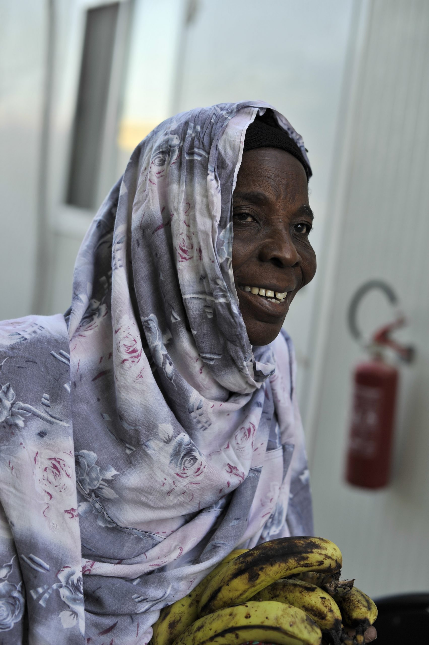 A smiling woman holding food items received during a community food distribution